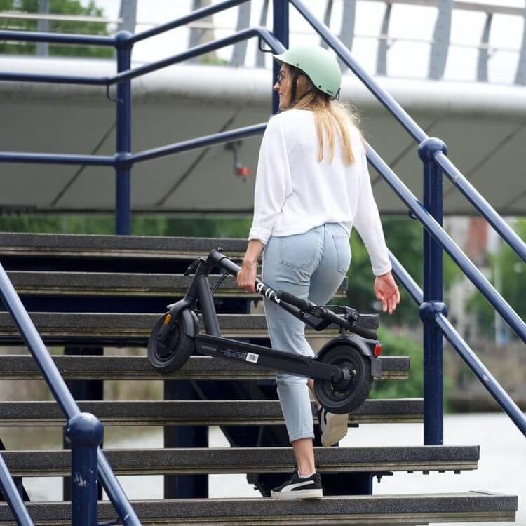 woman carrying the e-scooter up a flight of stairs