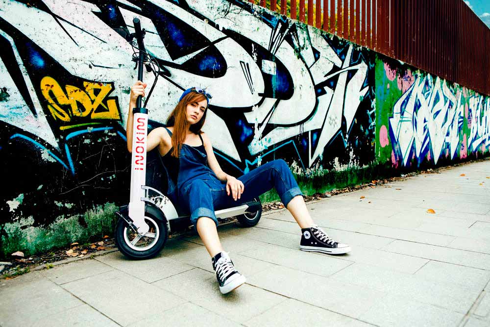 woman sat on pavement with her Quick 3 Inokim electronic scooter