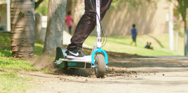 Green Razor E300 electric scooter being ridden on mud and pavement